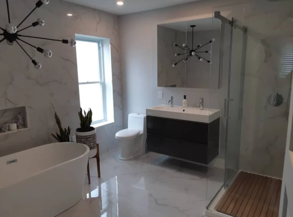 Large bathroom project by BWB Construction in Hamilton, Ontario, including a modern light, bathtub, vanity, toilet, and shower